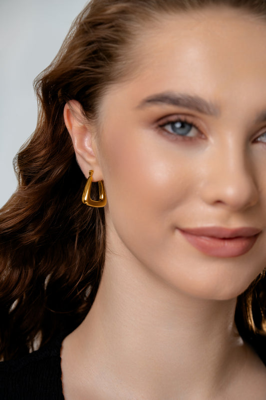 Model wearing Triangular Hoop Earrings showcasing their bold gold tone and stylish triangular shape for elegant accessorizing.