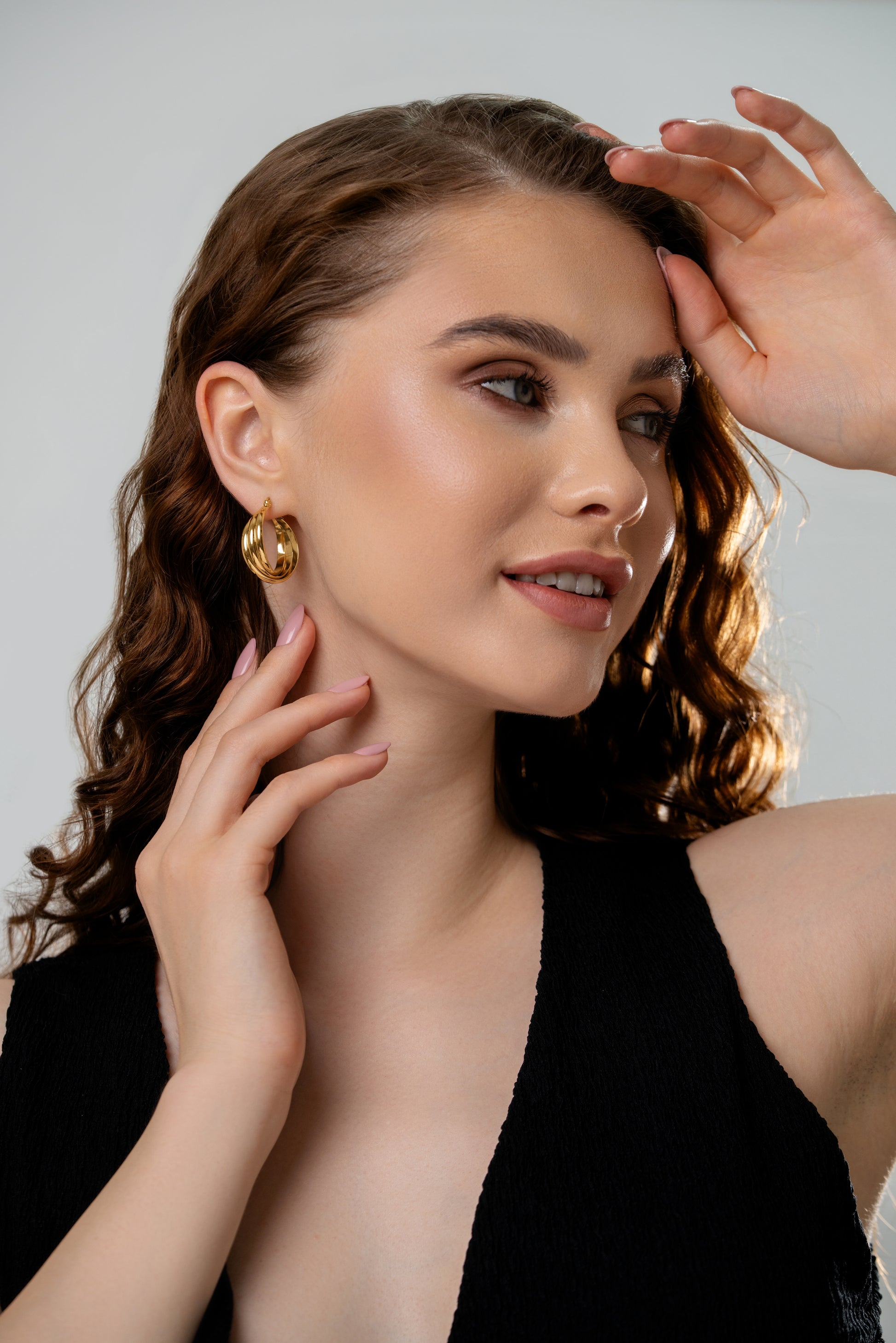 Model wearing Refined Oval Hoop Earrings in gold, showcasing elegant design for fashion-forward jewelry lovers. Ideal for formal and casual outfits.