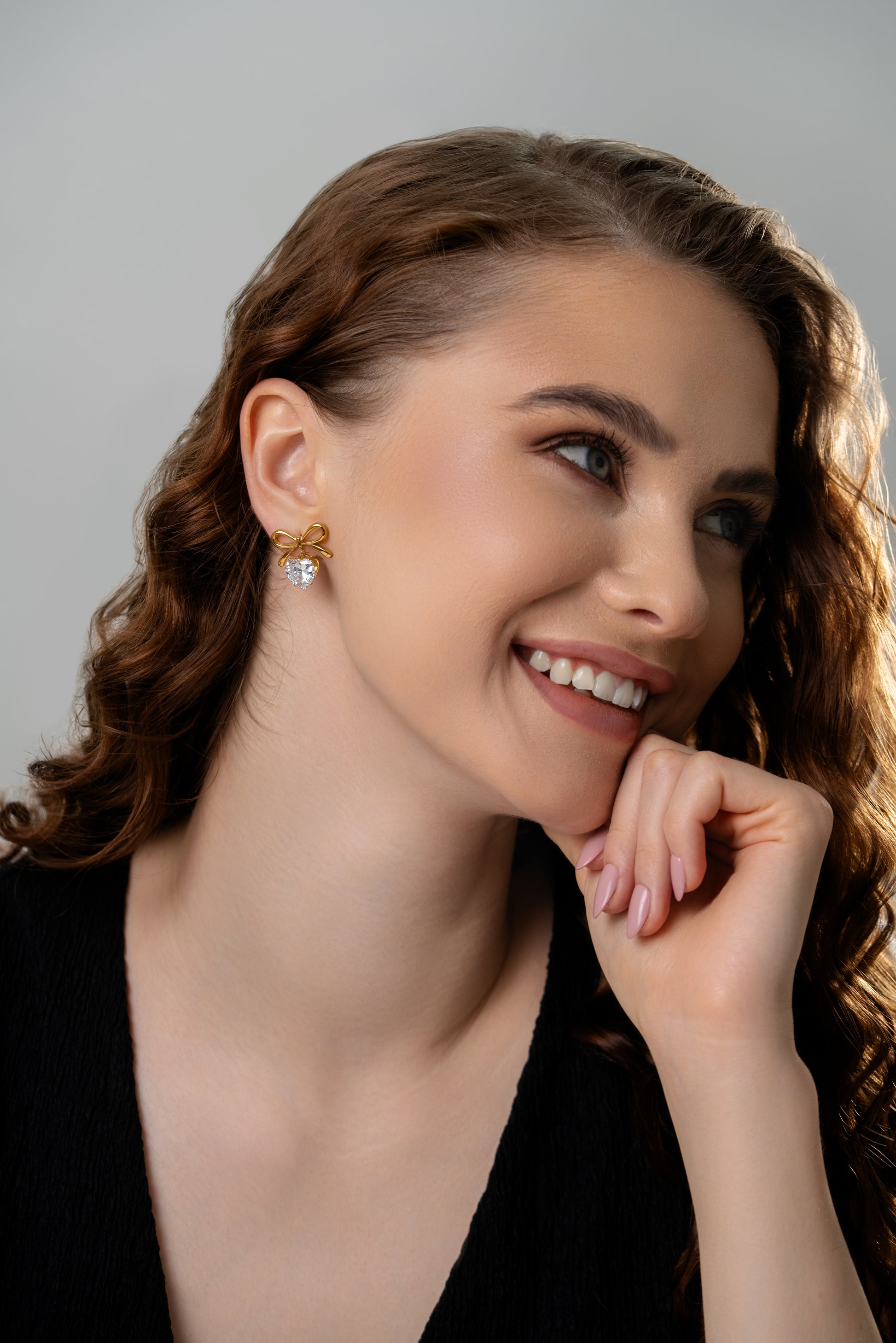 Close-up of model smiling while wearing The Bow Sparkle Studs, emphasizing their elegant and charming appeal for everyday glam.