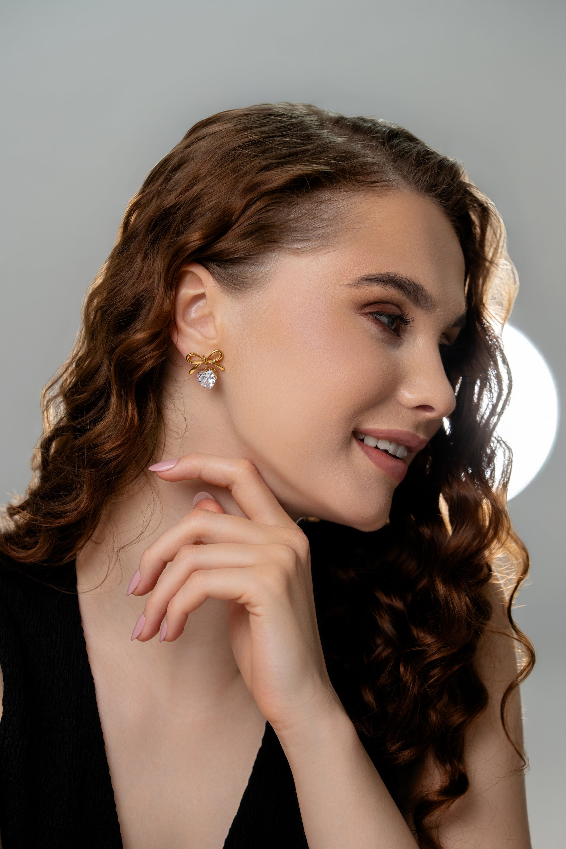 Model wearing The Bow Sparkle Studs, showcasing their gold bow and heart crystal design for a chic and feminine jewelry style.