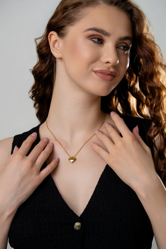 Model wearing gold chain necklace with heart pendant, highlighting its stylish fit for fashion-forward jewelry lovers.