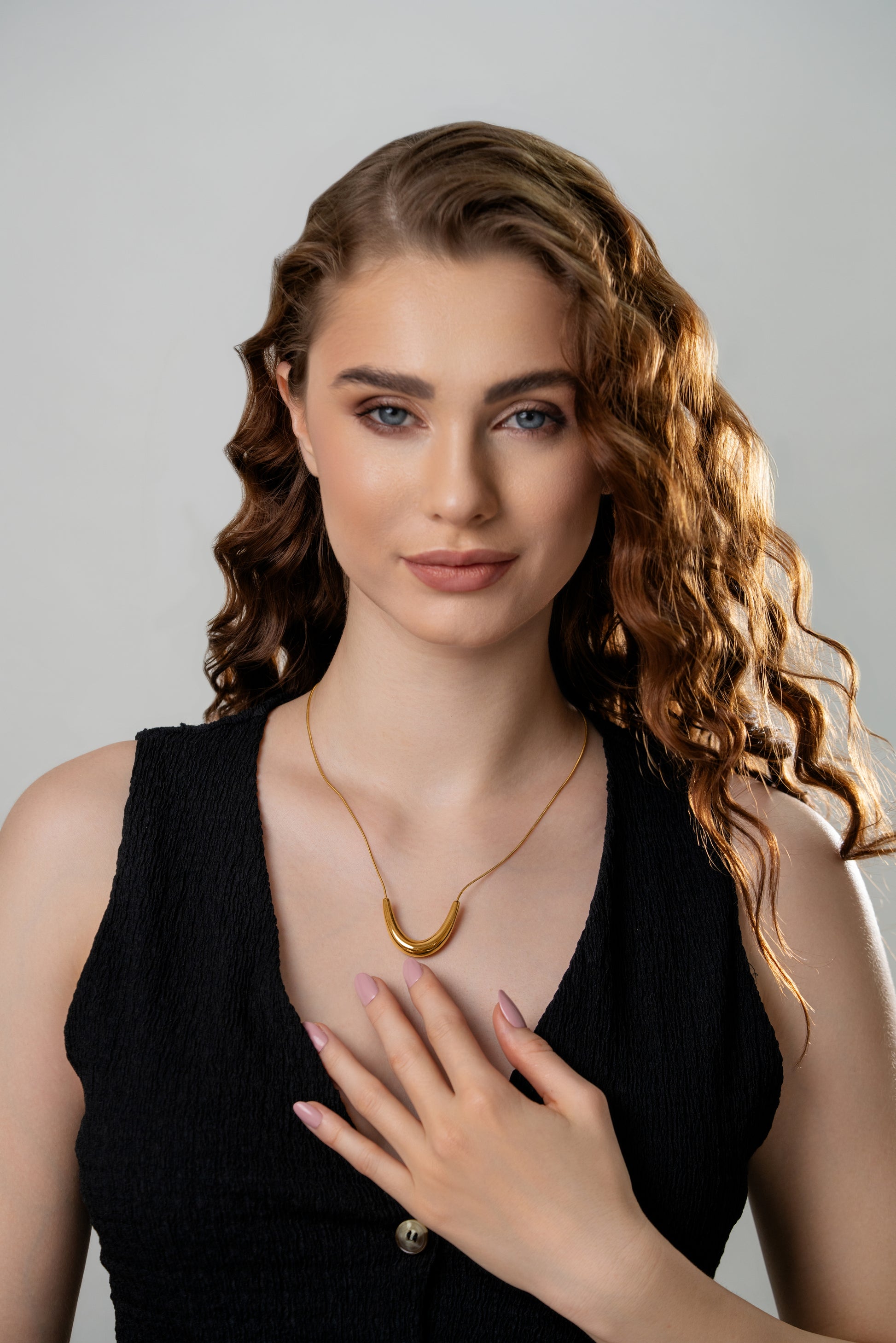 Model wearing The Arc gold necklace, highlighting its modern curved pendant and delicate chain for a chic, everyday jewelry look.
