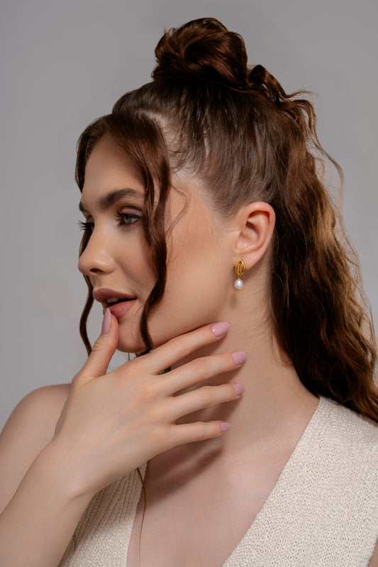 Model wearing Ocean's Embrace Pearl Earrings, showcasing elegant gold and pearl drop design perfect for summer and coastal fashion styles.
