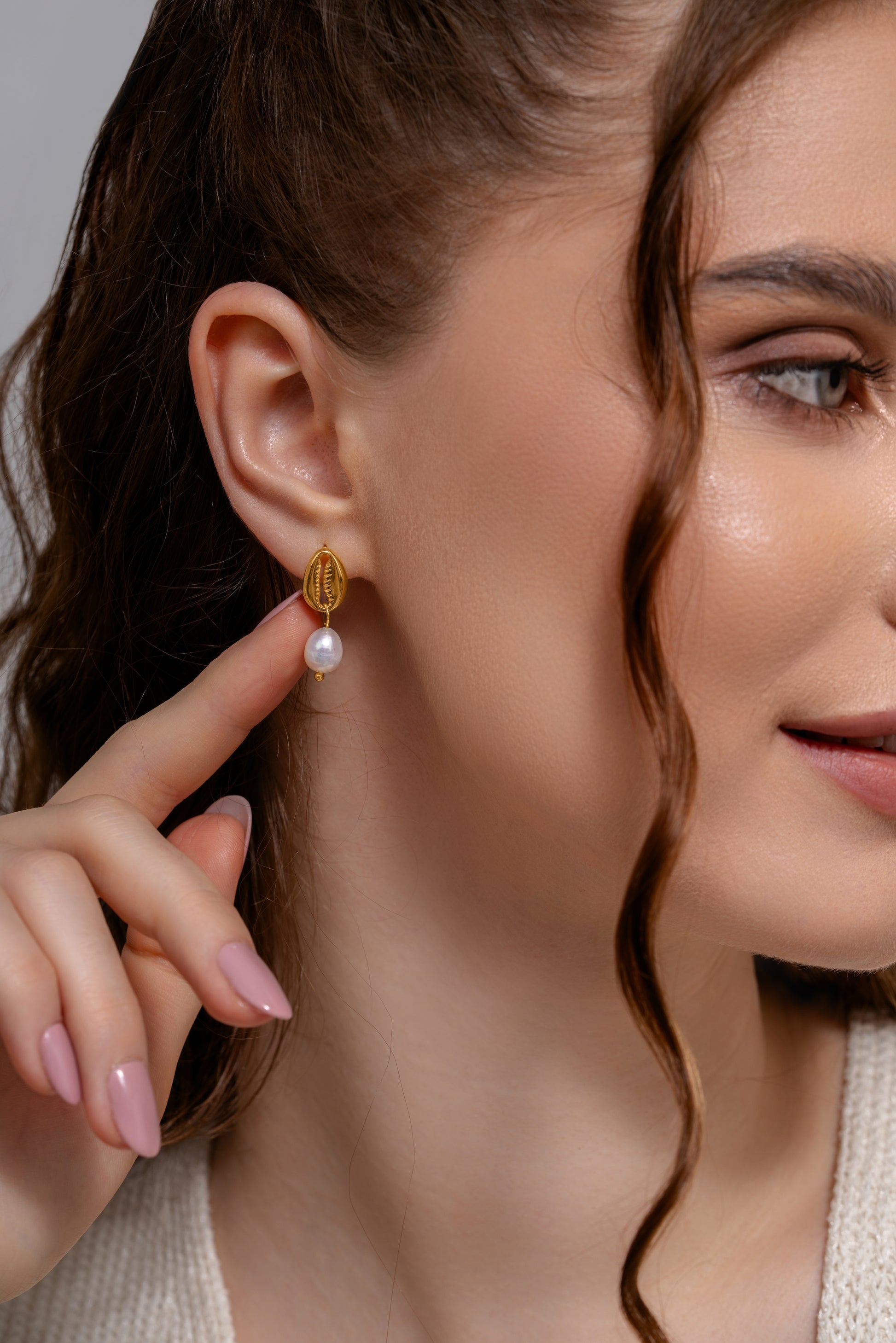 Close-up of Ocean's Embrace Pearl Earrings worn by model, emphasizing the delicate gold and pearl combination for chic accessory styling.