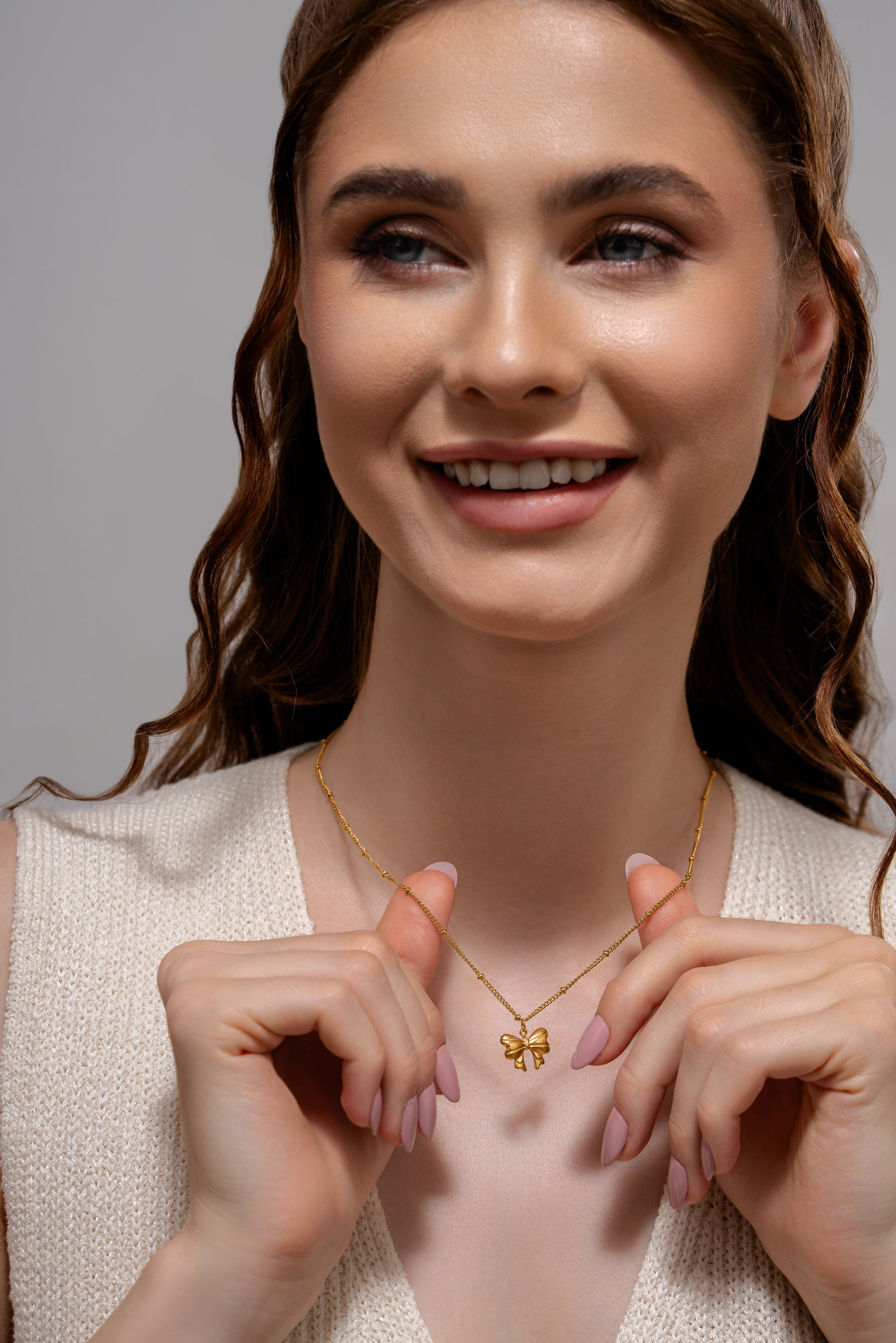 Close-up of smiling woman wearing Glimmerwing Gold Necklace, highlighting the pendant's intricate butterfly shape and gold finish.