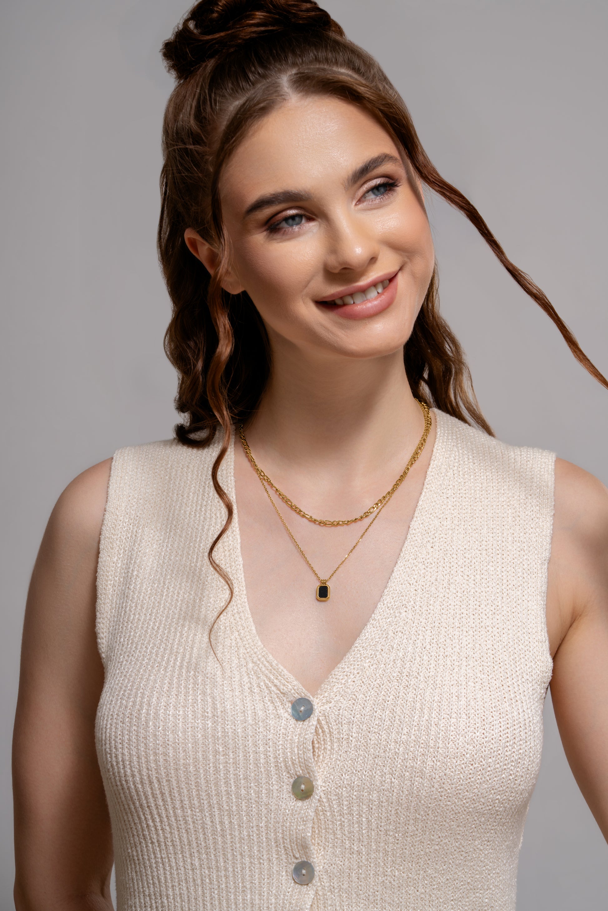 Model wearing Black Onyx Layered Necklace with gold chains and black pendant, styled with a cream knit top for a modern jewelry look.