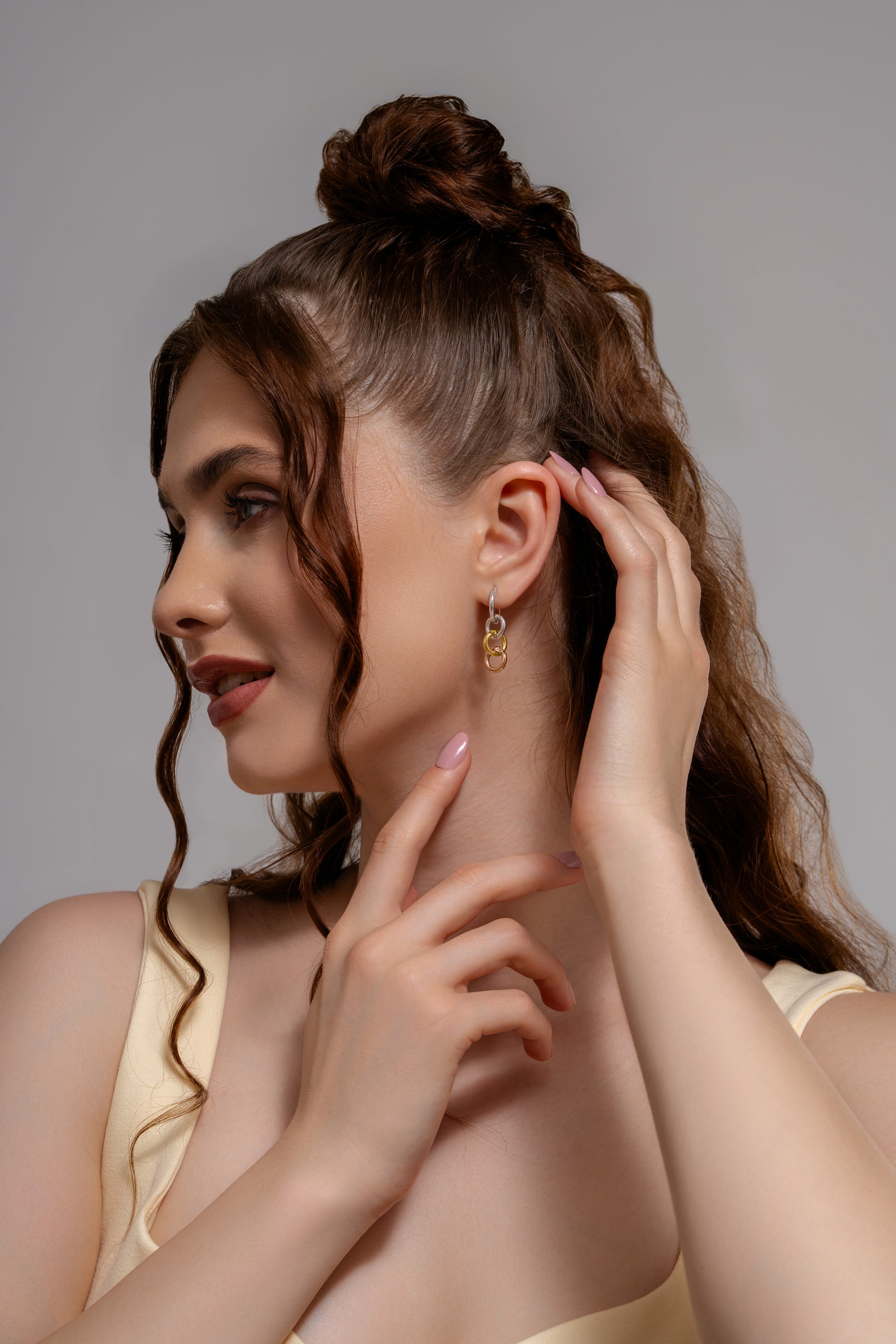 Side view of model showcasing Harmony Hoops earrings. Mixed metal design adds a chic touch to any outfit.