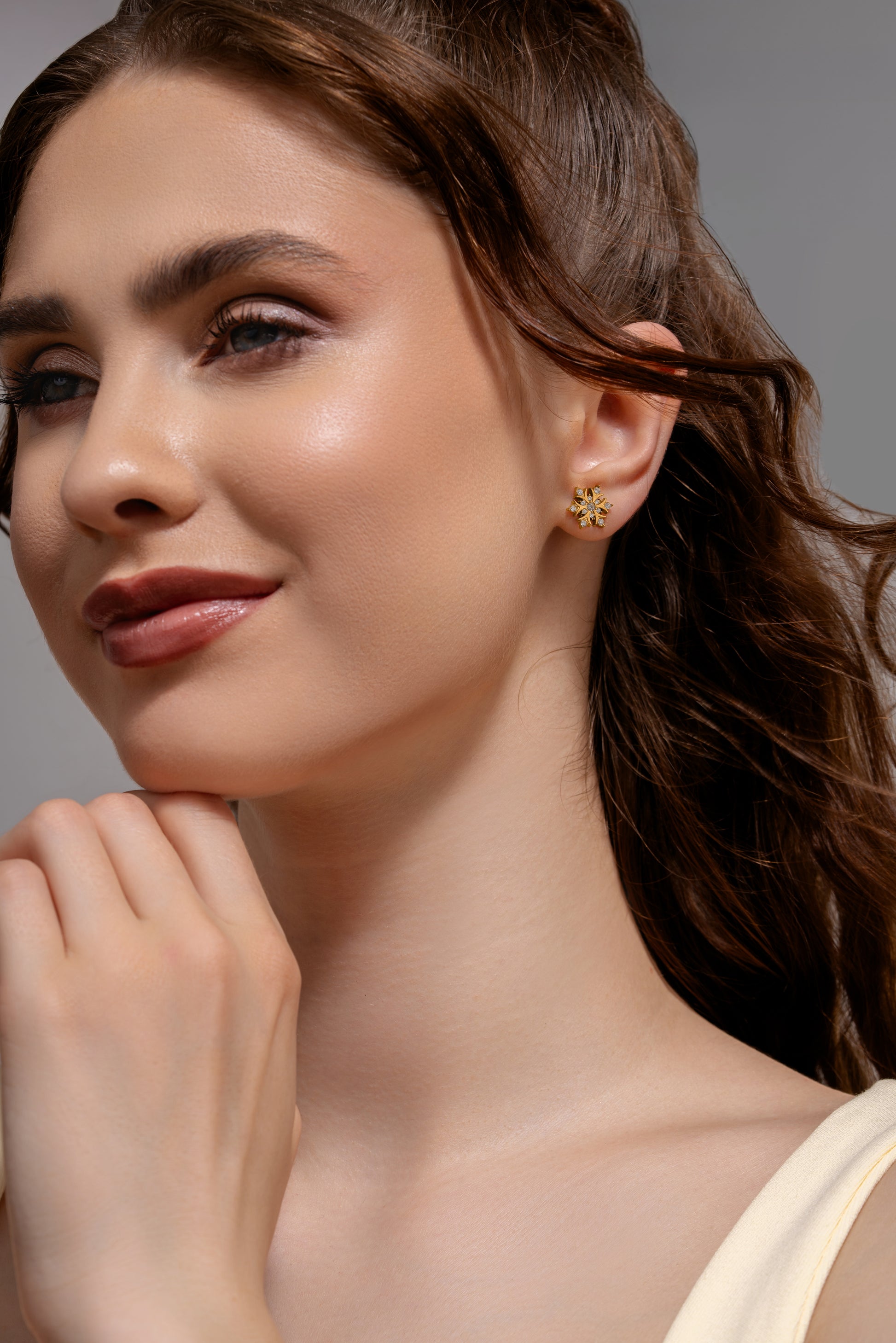 Model wearing Snowfall Diamond Earrings, showcasing gold snowflake studs with diamonds for a refined and festive accessory look.