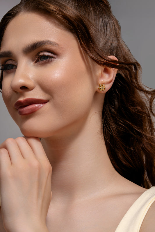 Model wearing Snowfall Diamond Earrings, showcasing gold snowflake studs with diamonds for a refined and festive accessory look.