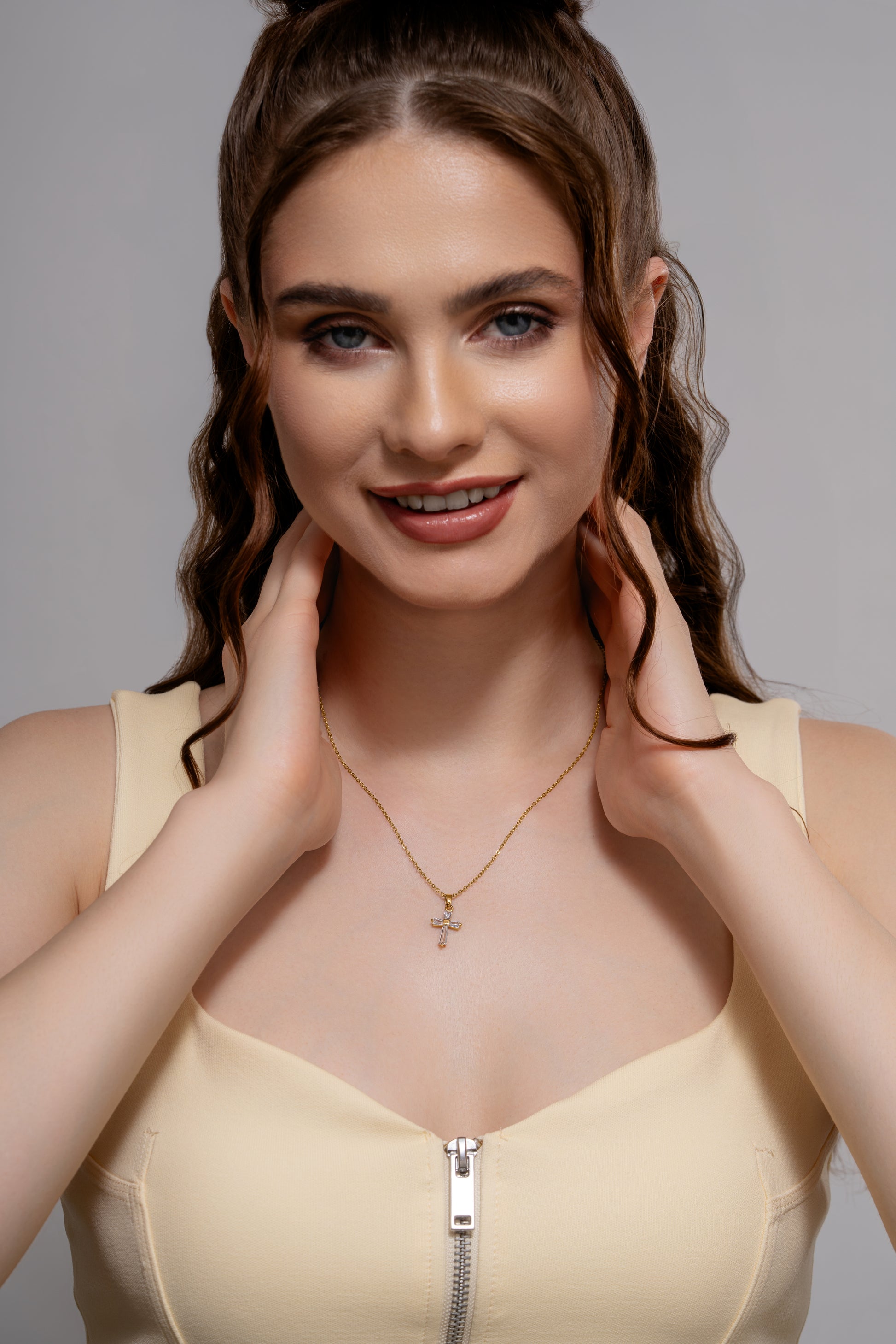 Smiling woman modeling a gold baguette pendant necklace, highlighting its stylish cross charm for fashion-forward jewelry shoppers.