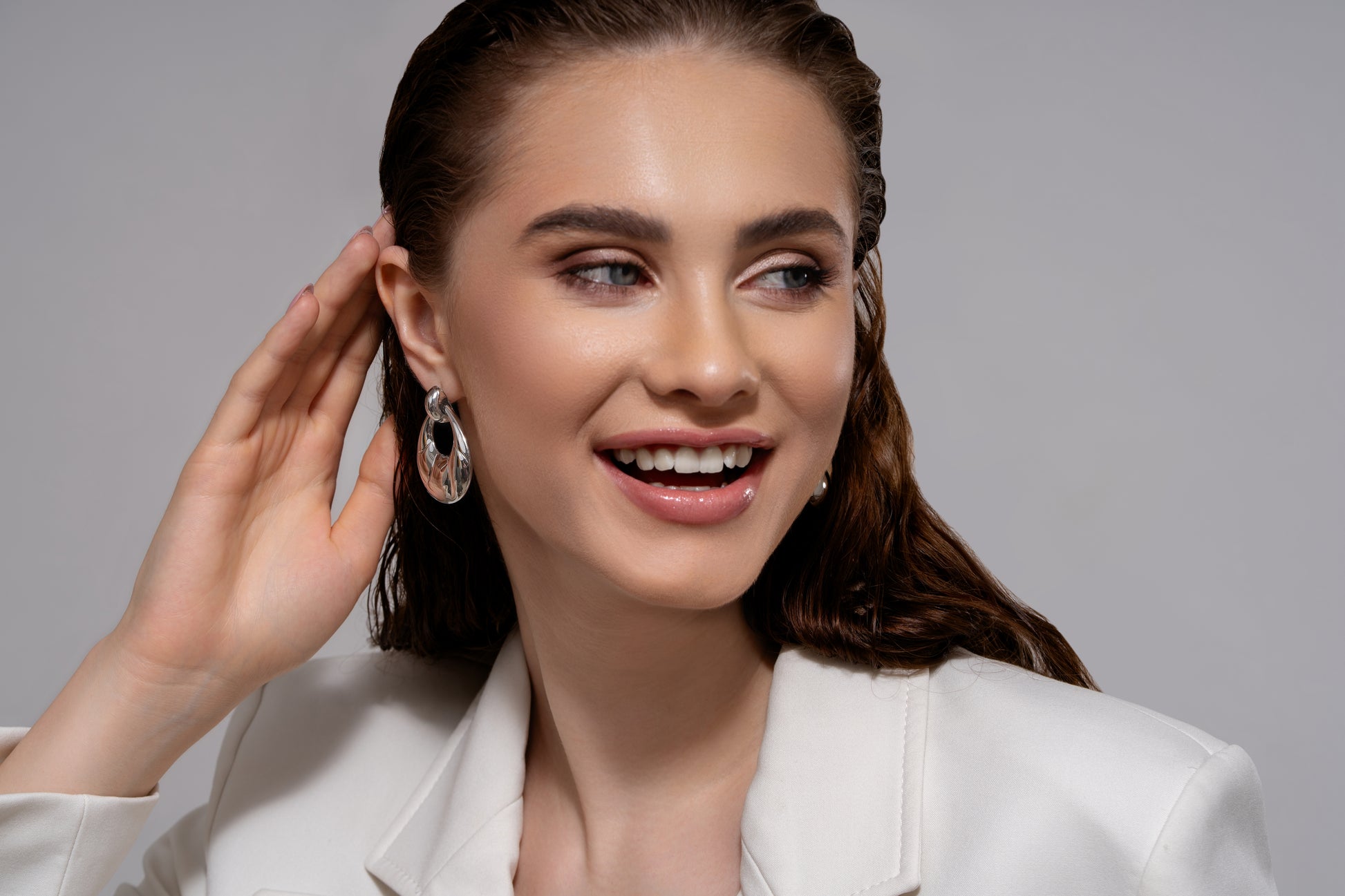 Twirléa Sterling Hoops worn by a smiling model, highlighting their bold, reflective design. Fashion-forward earrings for standout style.