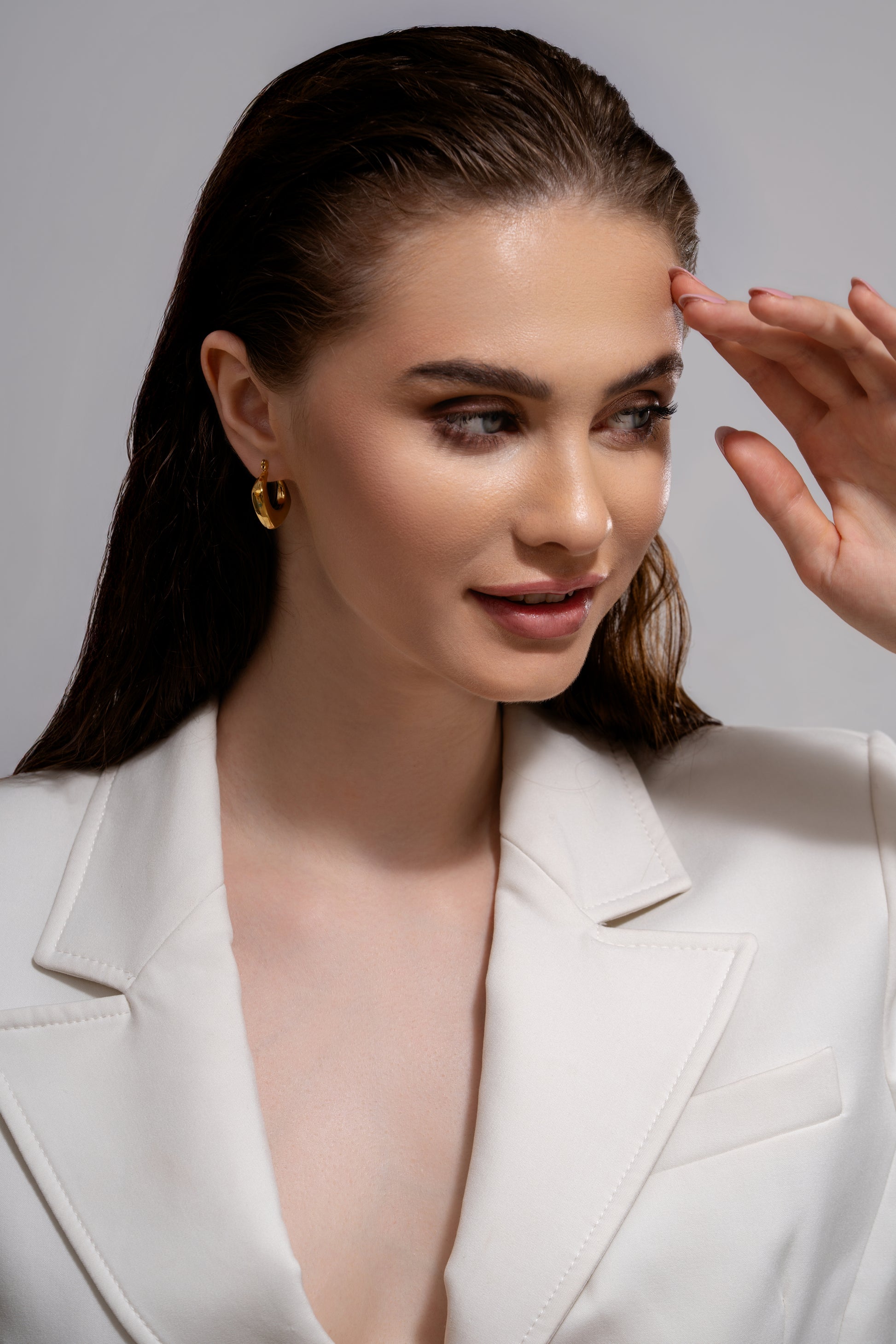 Model wearing Bold Geometric Gold Hoop Earrings styled with a white blazer, showcasing elegant and contemporary jewelry for formal looks.