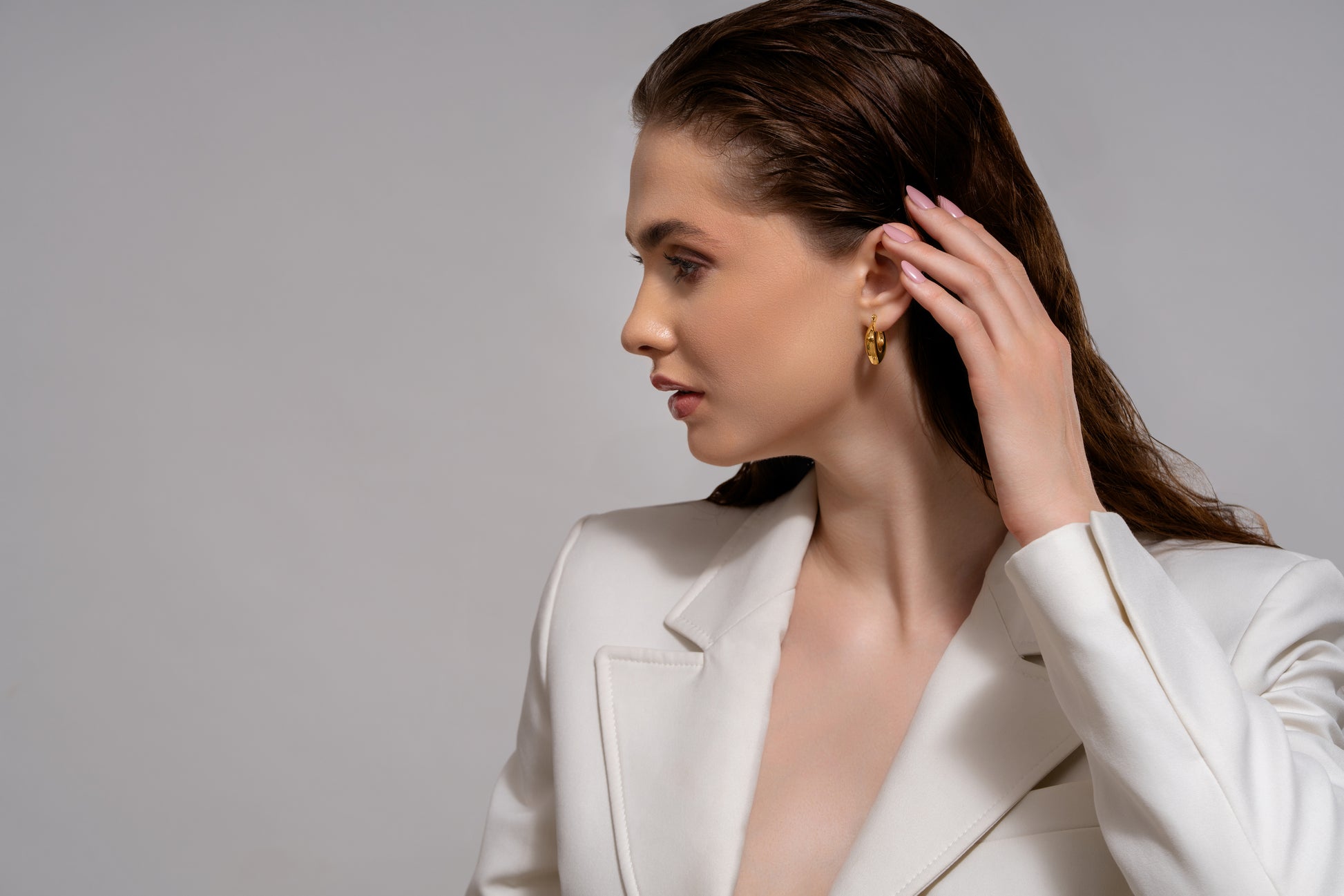 Side profile of model wearing Bold Geometric Gold Hoop Earrings, highlighting their unique shape and shine for upscale fashion appeal.