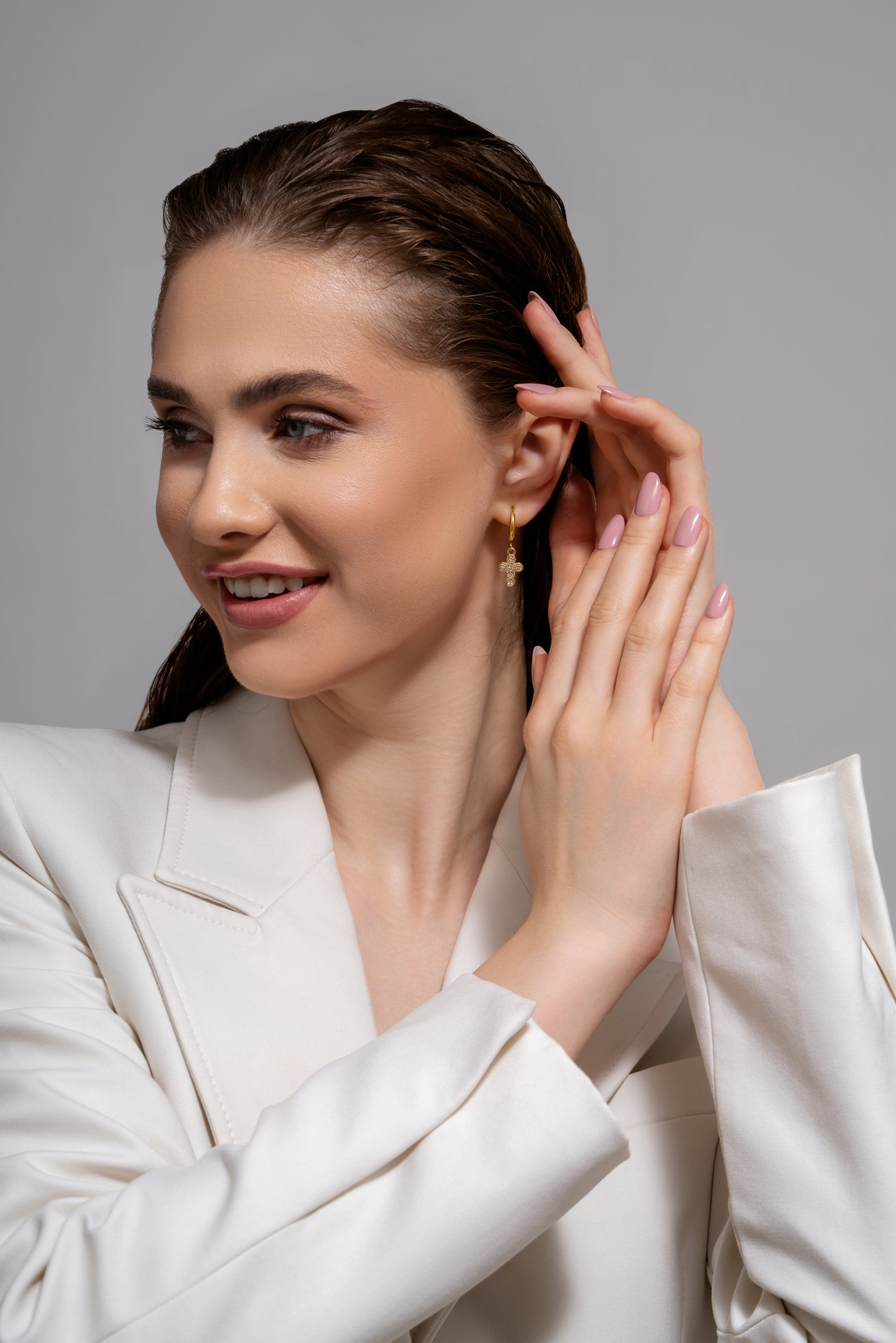 Smiling model displaying gold cross earrings, perfect for showcasing their elegance in everyday or formal wear.
