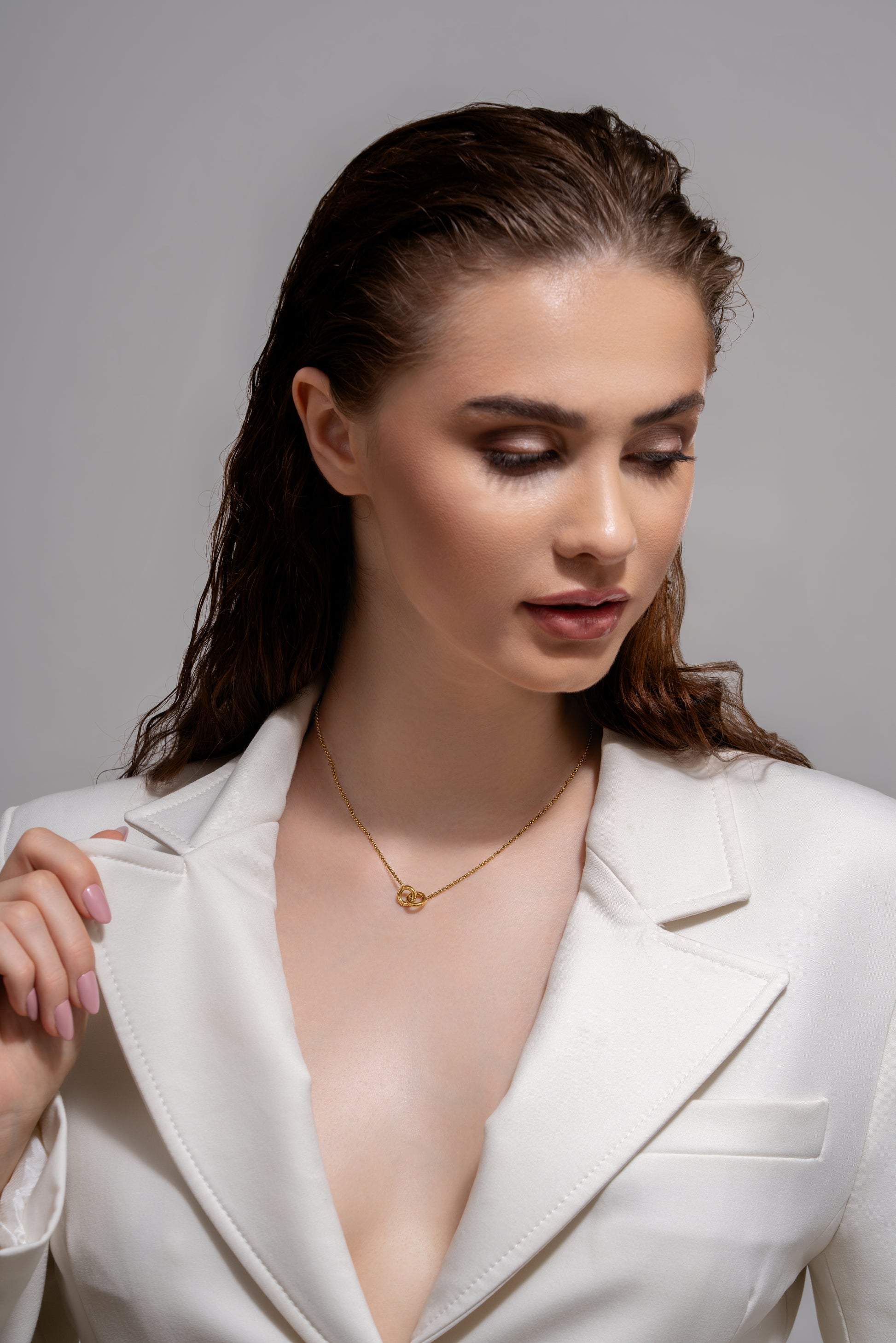 Eternal Grace Necklace styled on model in white blazer, highlighting its refined gold pendant perfect for formal and casual fashion looks.
