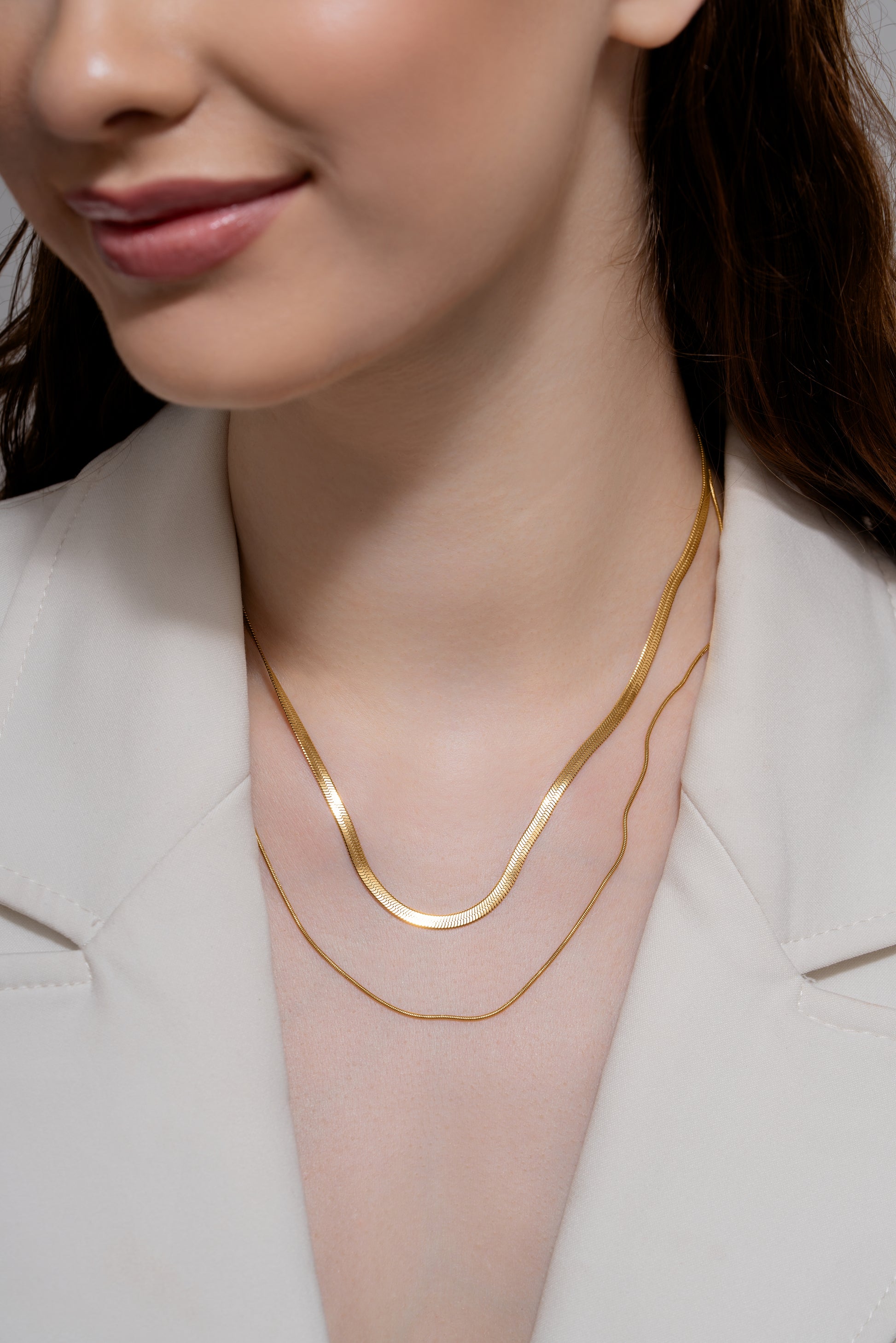 Layered Duo Necklace featuring two sleek gold chains styled on a woman wearing a white blazer, ideal for elegant and minimalist looks.