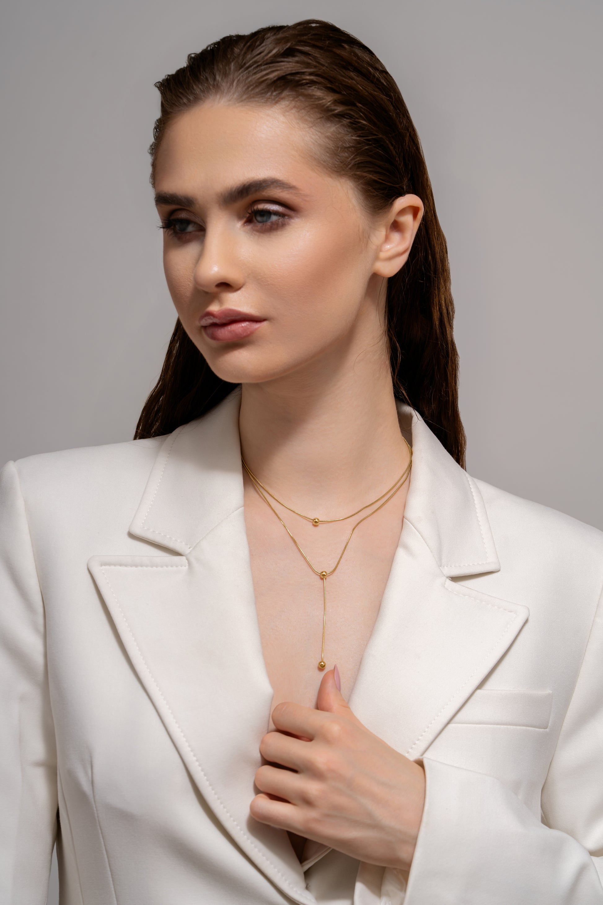 Model wearing Beaded Drop Necklace with a white suit, highlighting the necklace's Y-shape and gold bead details for a chic fashion statement.