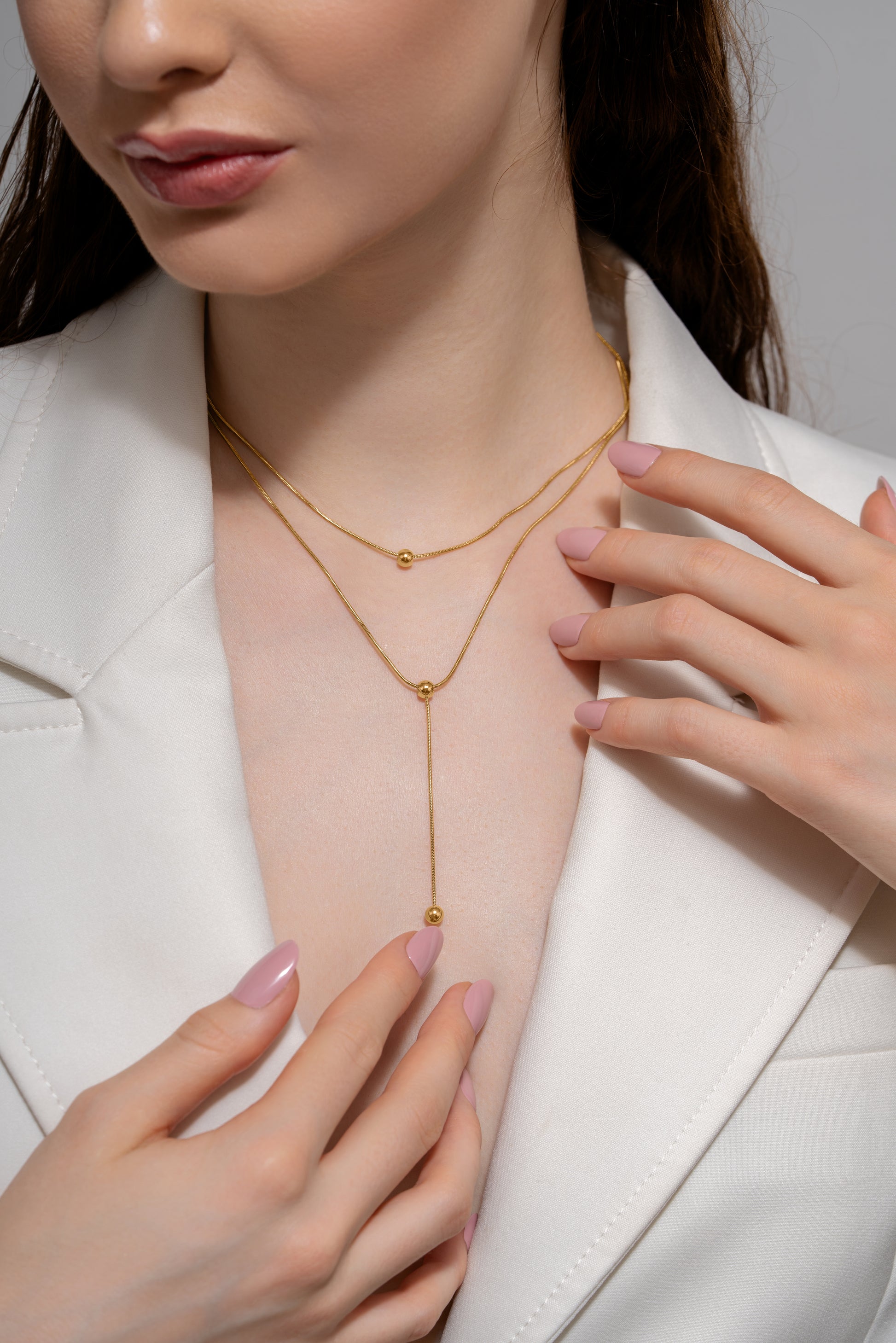 Beaded Drop Necklace styled on a model wearing a white blazer, showcasing its delicate layered design and gold bead accents for formal wear.