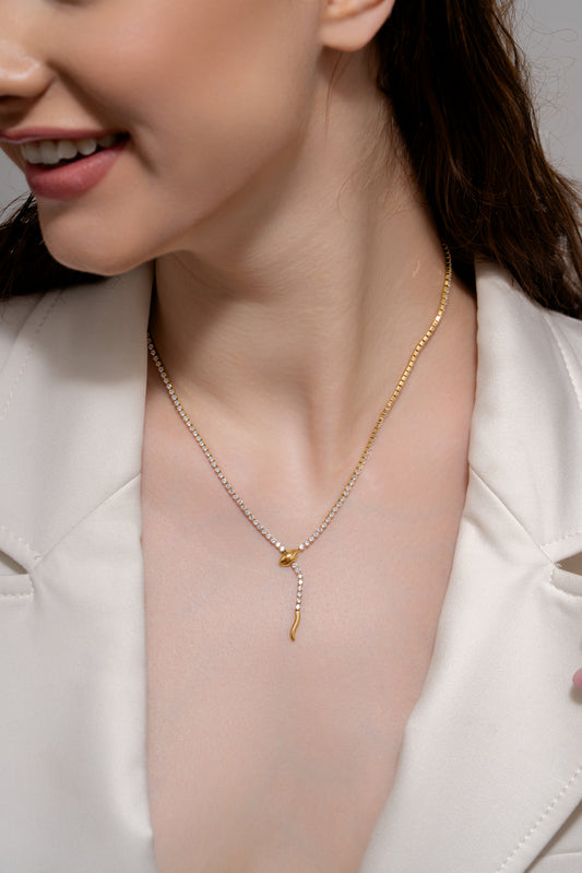Model wearing the Serpent's Embrace Necklace with a white blazer, showcasing its luxurious gold and diamond snake motif for upscale fashion.