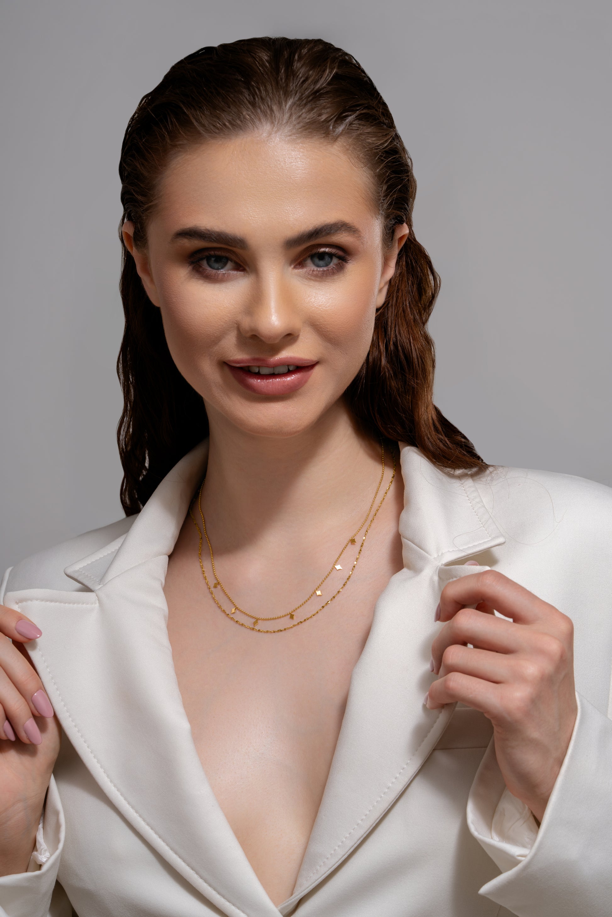 Dusk Gleam Layered Chain showcased on model in white blazer, highlighting its delicate gold layers and modern geometric design for upscale styling.