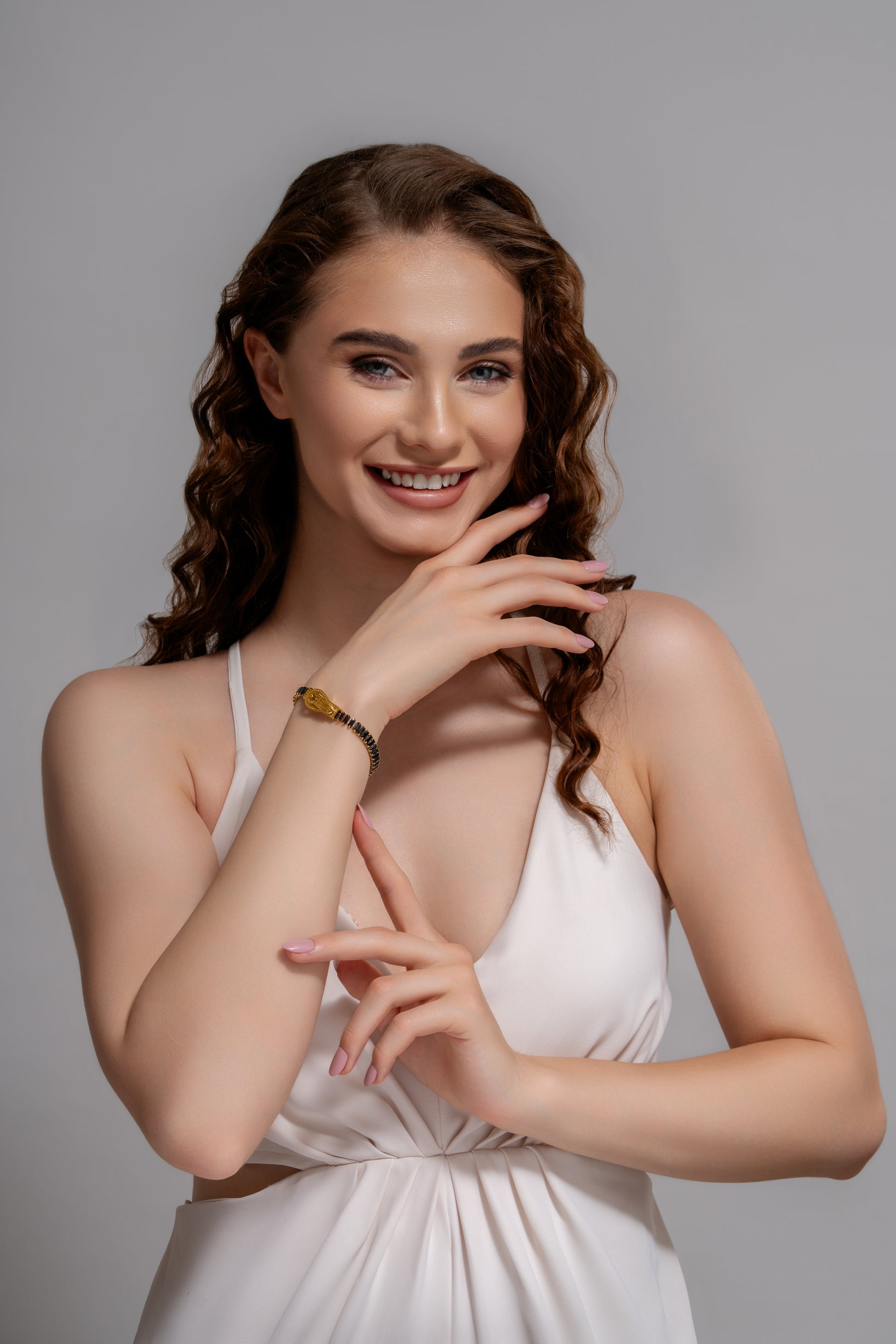Model smiling in white dress while displaying Baguette Tennis Bracelet, a chic accessory for upscale jewelry collections.