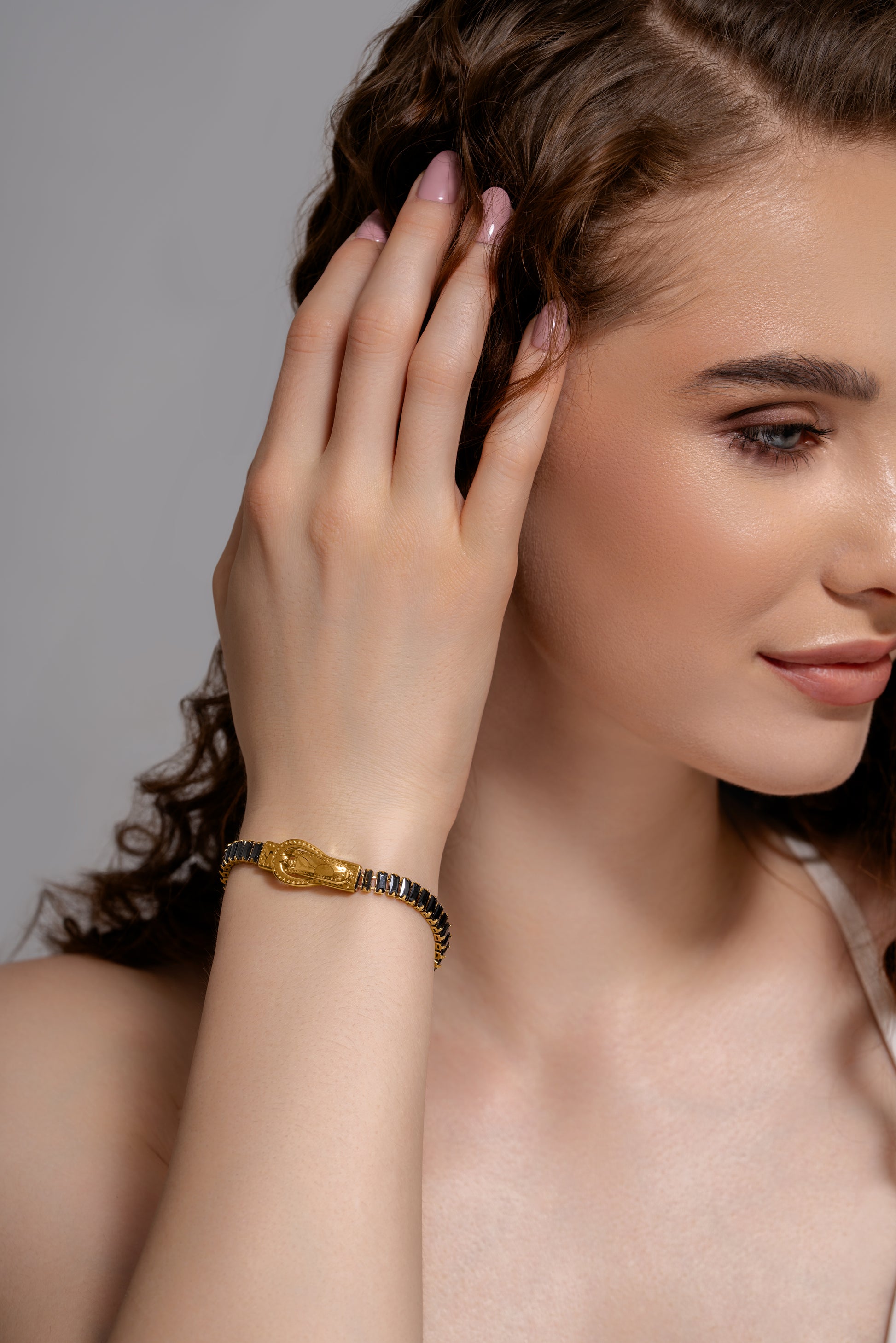 Woman wearing a Baguette Tennis Bracelet with gold buckle design and black baguette stones, showcasing elegant wrist jewelry.