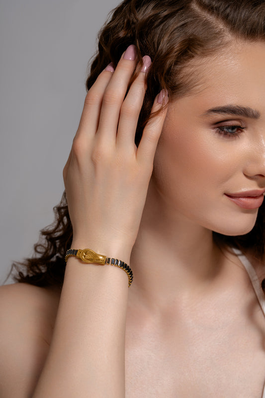Woman wearing a Baguette Tennis Bracelet with gold buckle design and black baguette stones, showcasing elegant wrist jewelry.