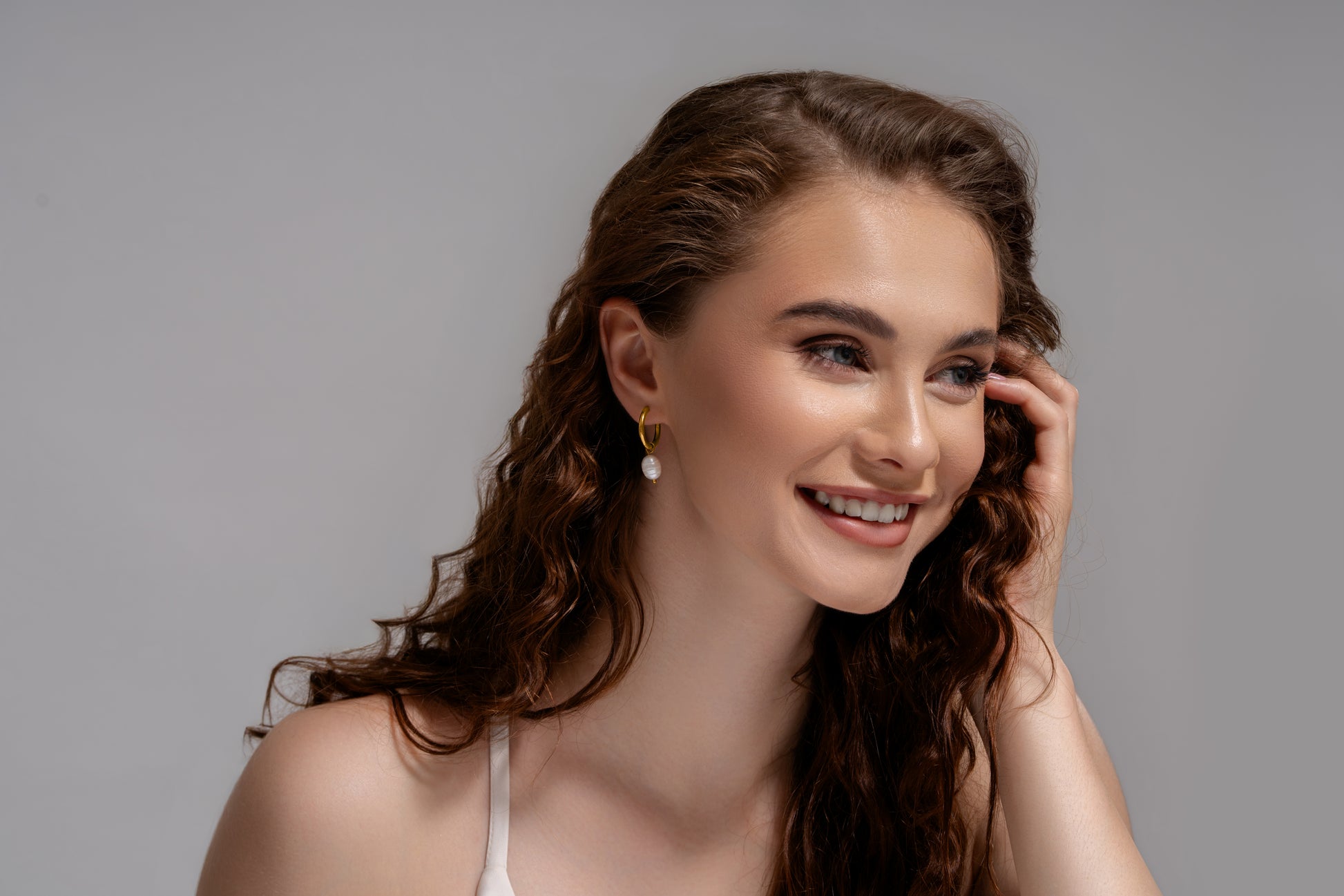 Smiling model styled with Luna Pearl Drop Earrings, highlighting their delicate gold and pearl combination for chic accessorizing.