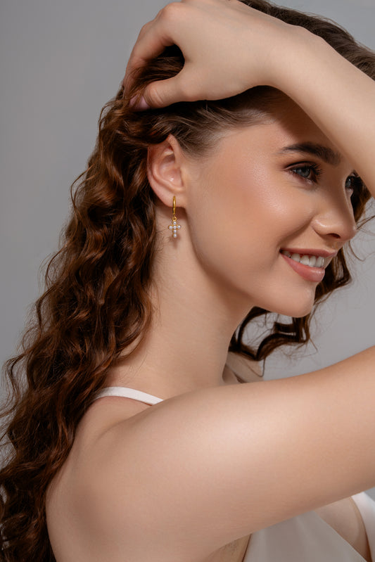 Model wearing Grace Pearl Hoops, showcasing delicate gold hoops with pearl cross charms, perfect for chic and modern accessorizing.