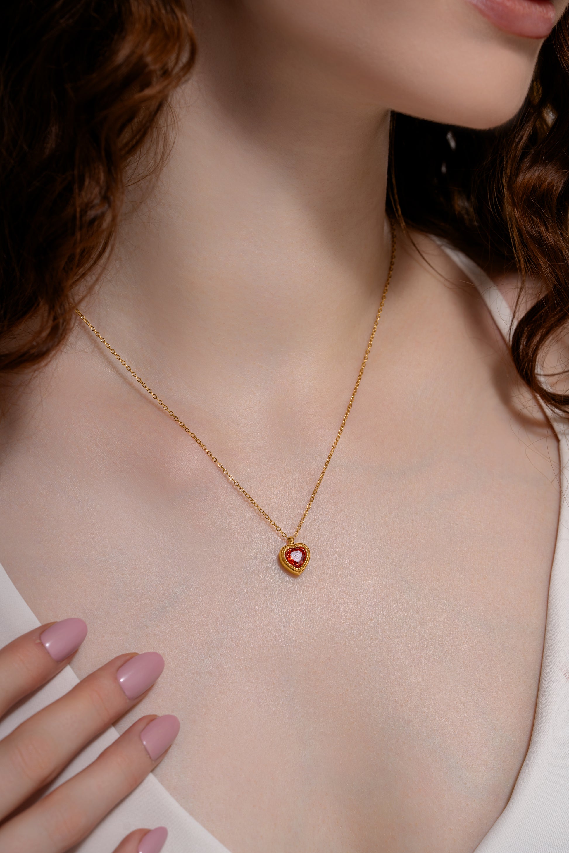 Close-up of the Crimson Heart Pendant on model’s neck, showcasing the red heart gemstone and fine gold chain for a refined accessory detail.