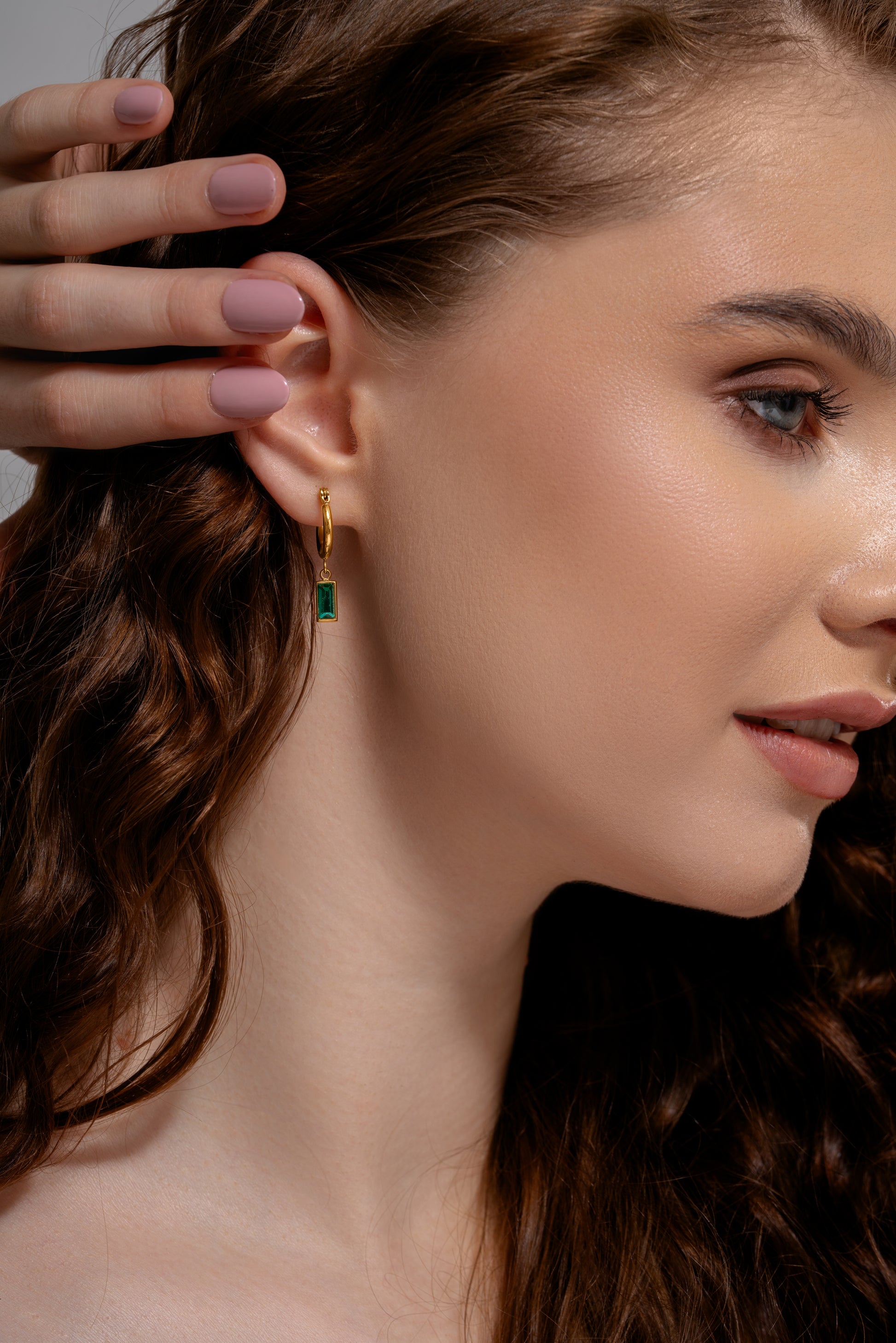 Close-up of model wearing Verdant Glow Emerald Drops, highlighting the vibrant emerald stone and gold hoop design for fashion-forward styling.