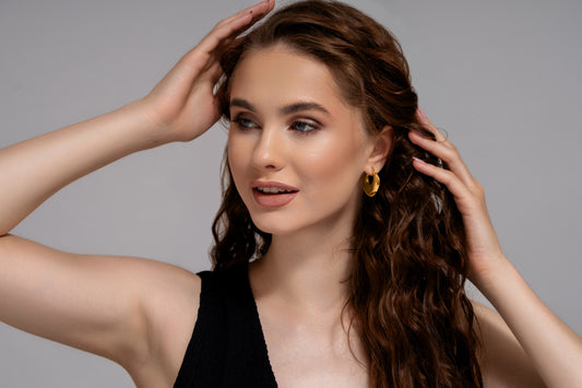 Model wearing Luna Bold Gold Hoops, showcasing their bold, glossy gold finish and elegant curve for a chic, modern look.