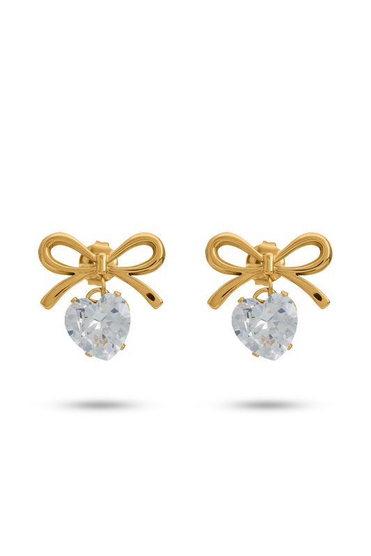 The Bow Sparkle Studs feature gold-tone bow designs with dangling heart-shaped crystals, perfect for elegant and romantic looks.