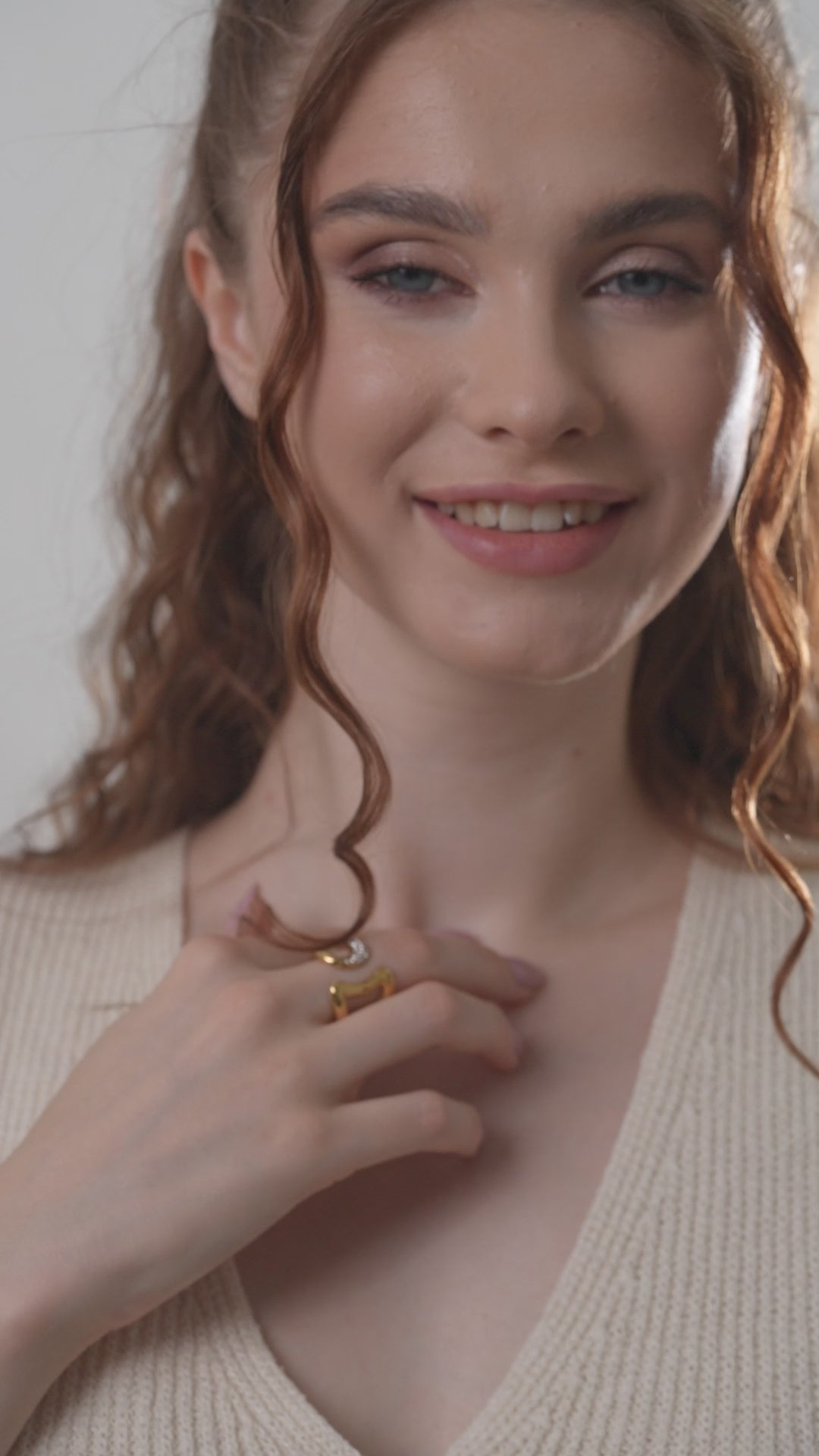 Smiling model displaying Gilded Spark Ring, emphasizing its luxurious gold tone and sparkling crystal accent for fashion-forward styling.