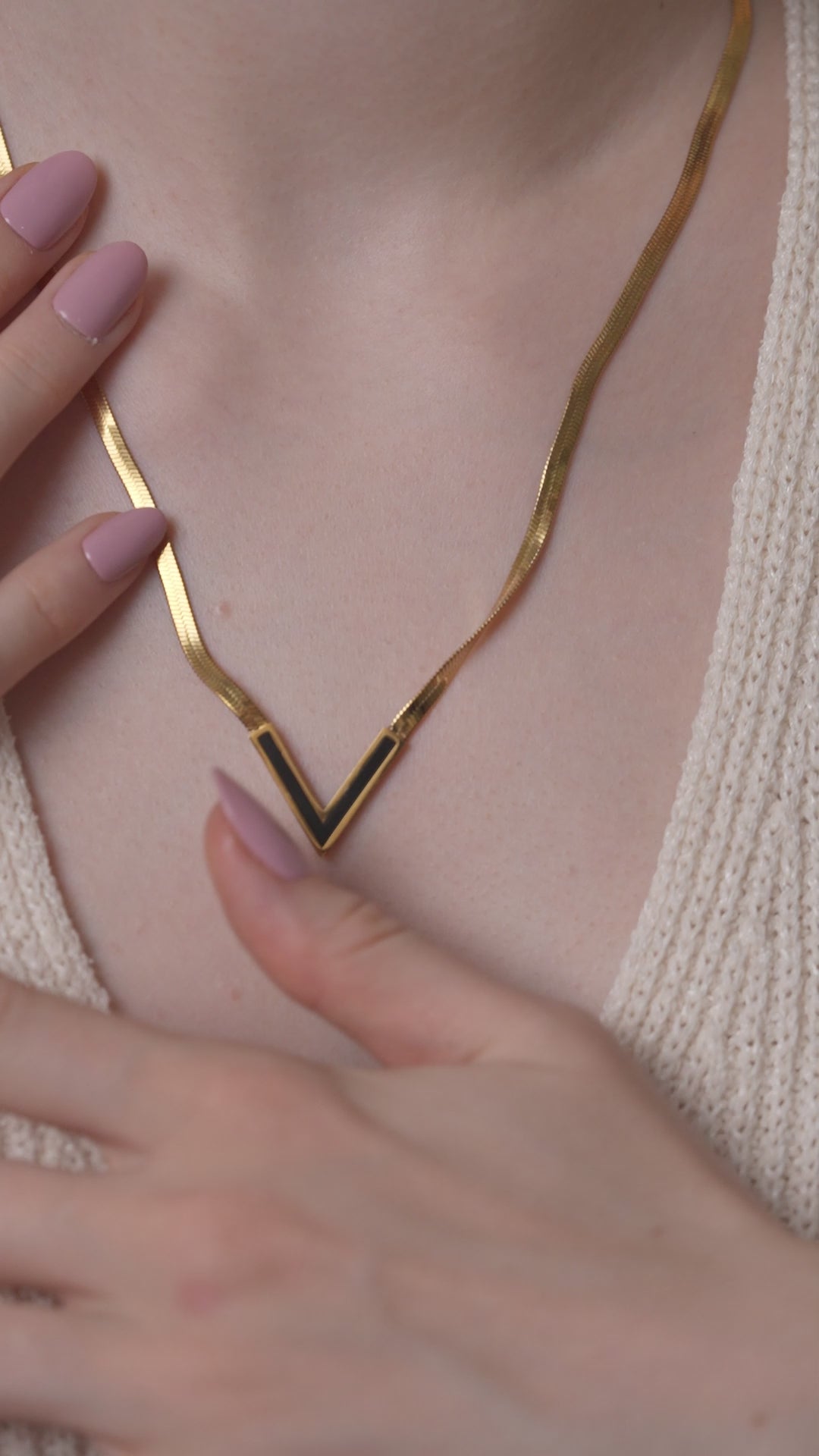 Detailed view of Bold V necklace on neckline, emphasizing the polished gold finish and sharp V-shaped pendant design.
