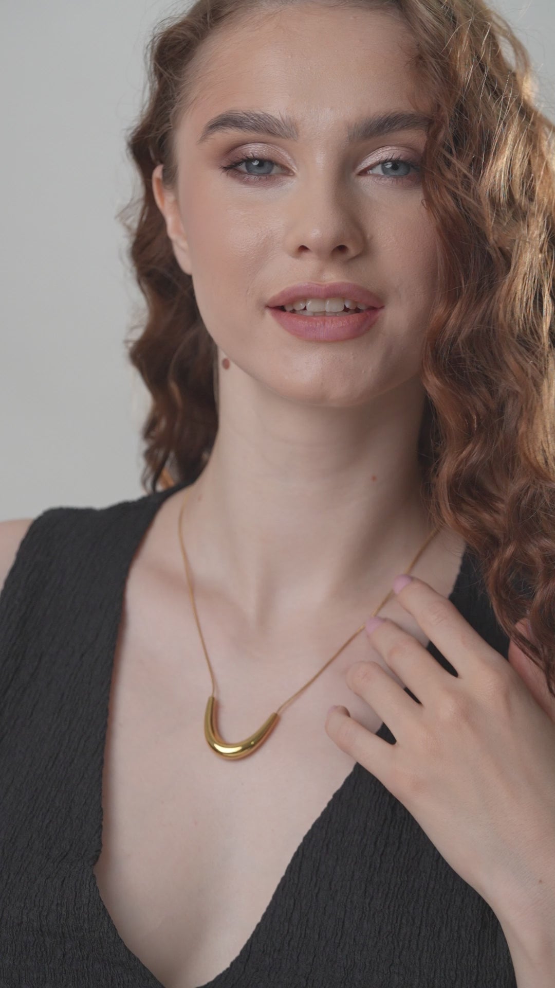 Close-up of The Arc gold necklace on model, emphasizing the polished curved pendant and sophisticated style in fine jewelry.