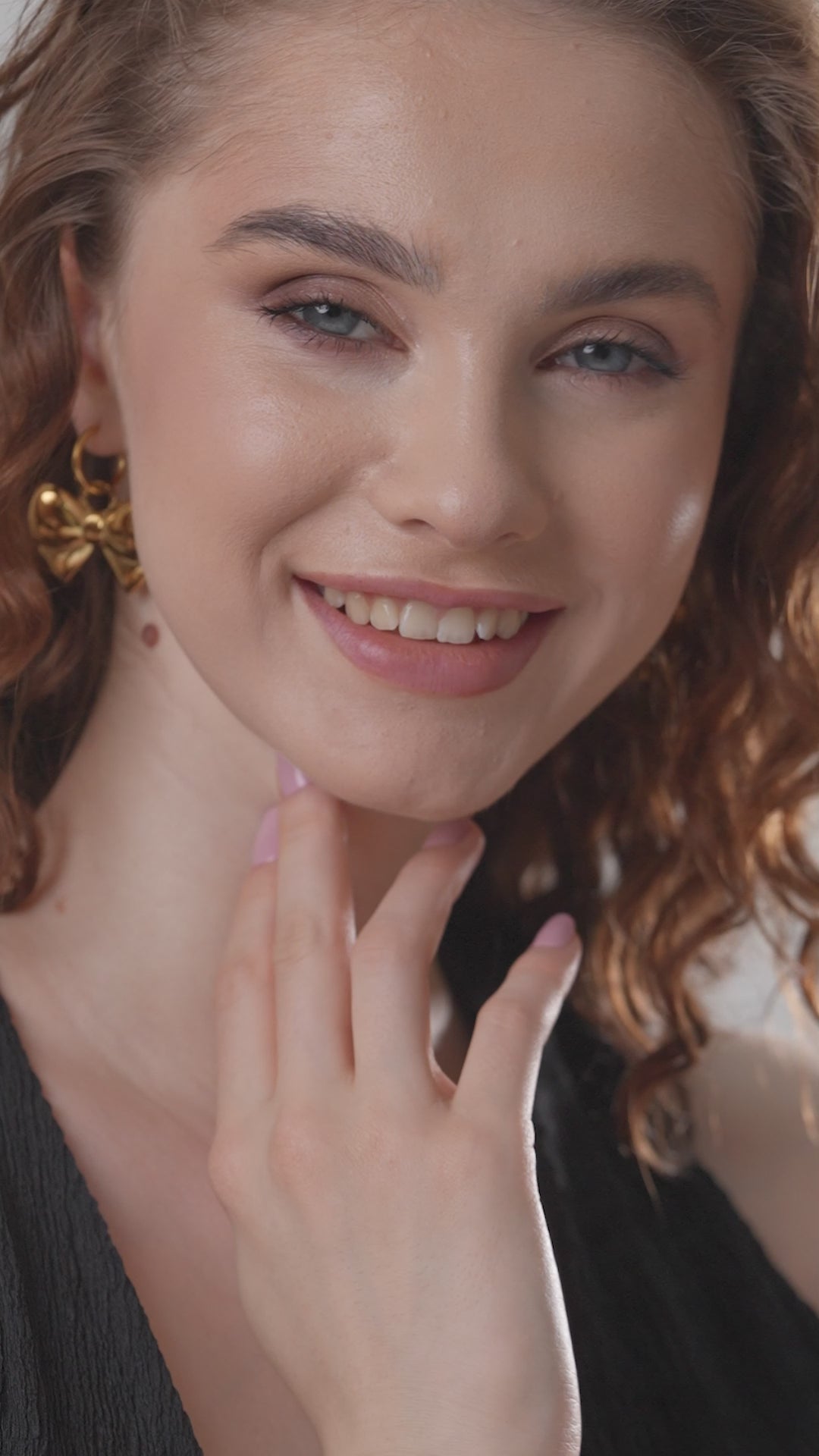 Close-up of model wearing Belle Bow Charm Earrings, emphasizing the glossy gold finish and chic bow design for trendy accessorizing.