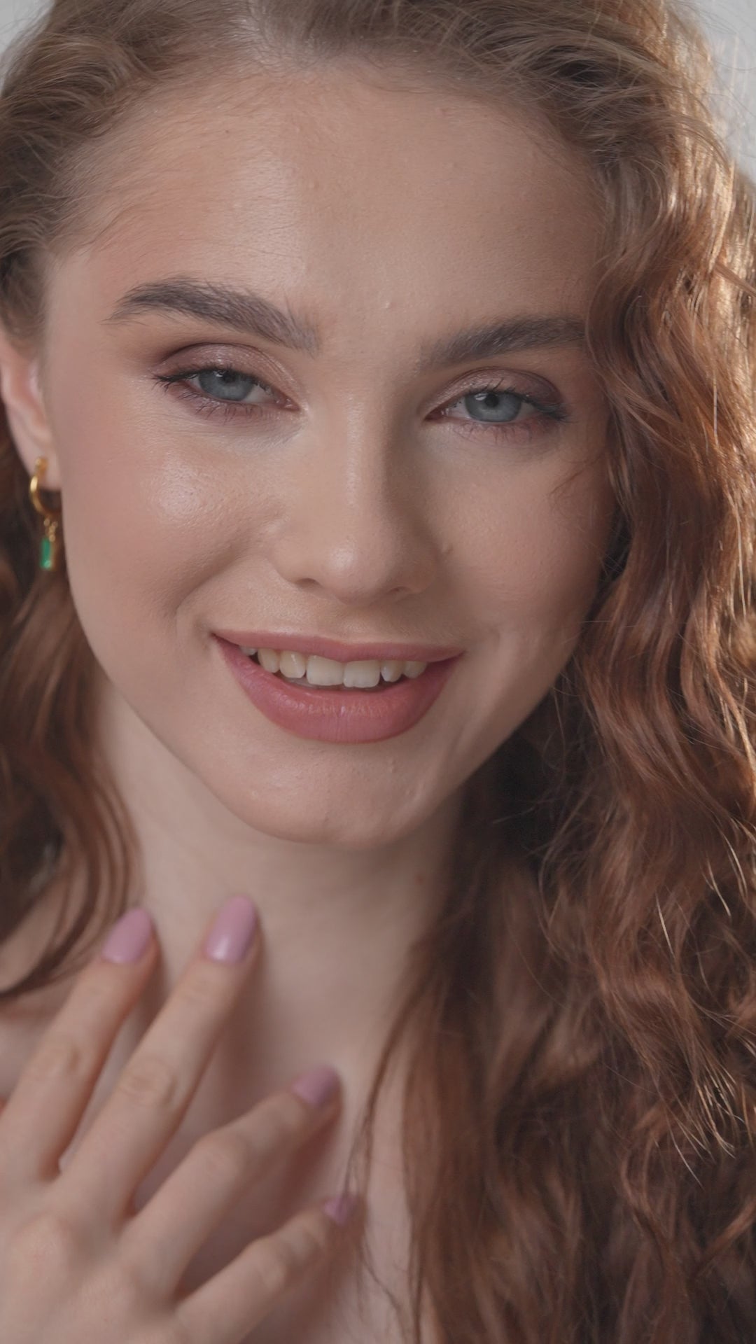 Smiling model wearing Verdant Glow Emerald Drops earrings, emphasizing the accessory's elegance and vibrant green gemstone appeal.