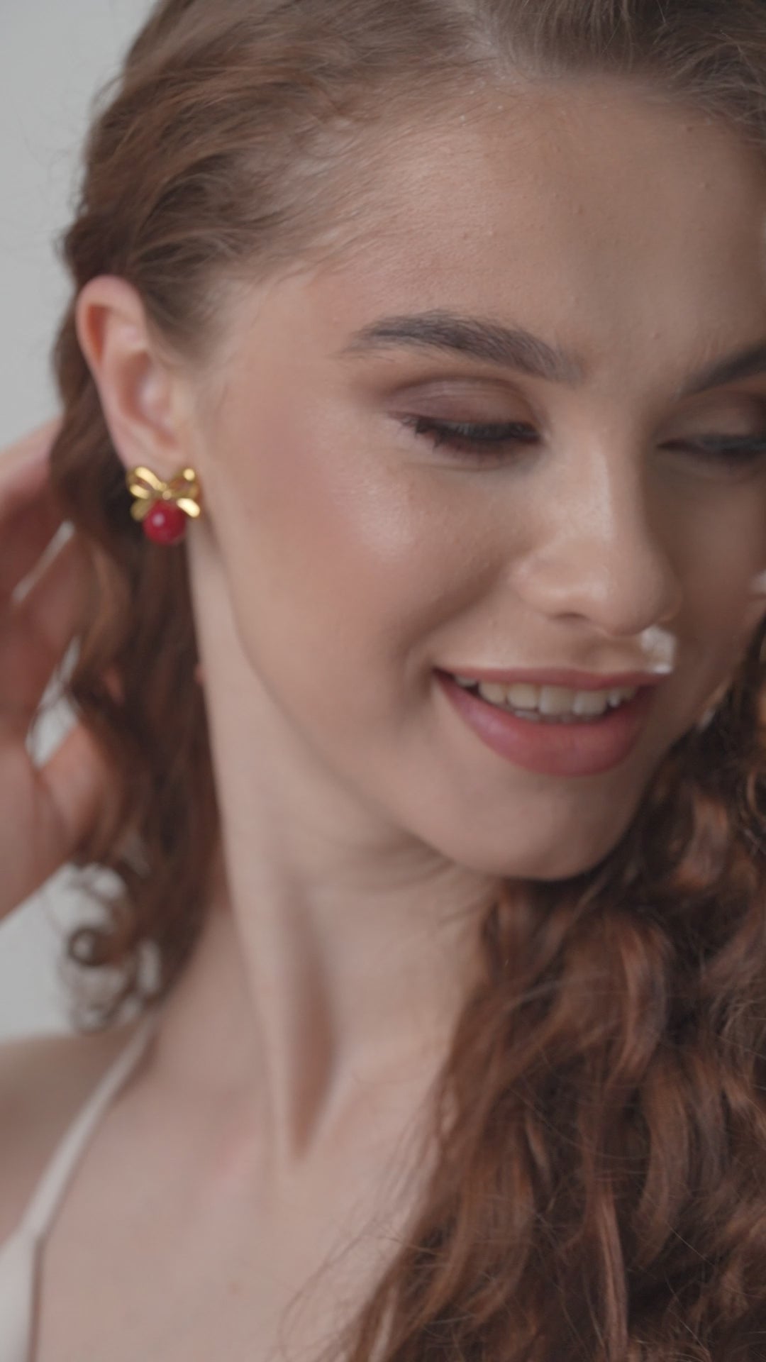 Close-up of woman wearing Red Orb & Gold Bow Stud Earring, emphasizing the accessory’s elegant gold bow and vivid red orb detail.