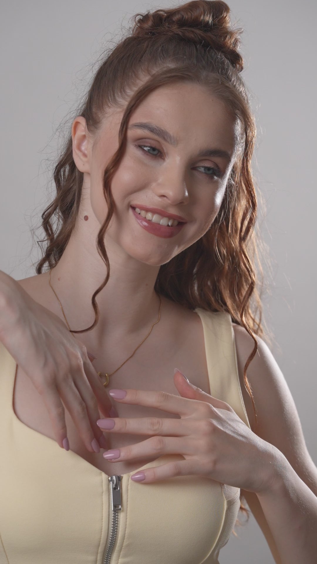 Model smiling while adjusting the Luna Charm Necklace, showcasing its dainty gold crescent design in a lifestyle setting.